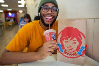 Person drinking a Pumpkin Spice Cold brew from wendy's next to a wendy's bag