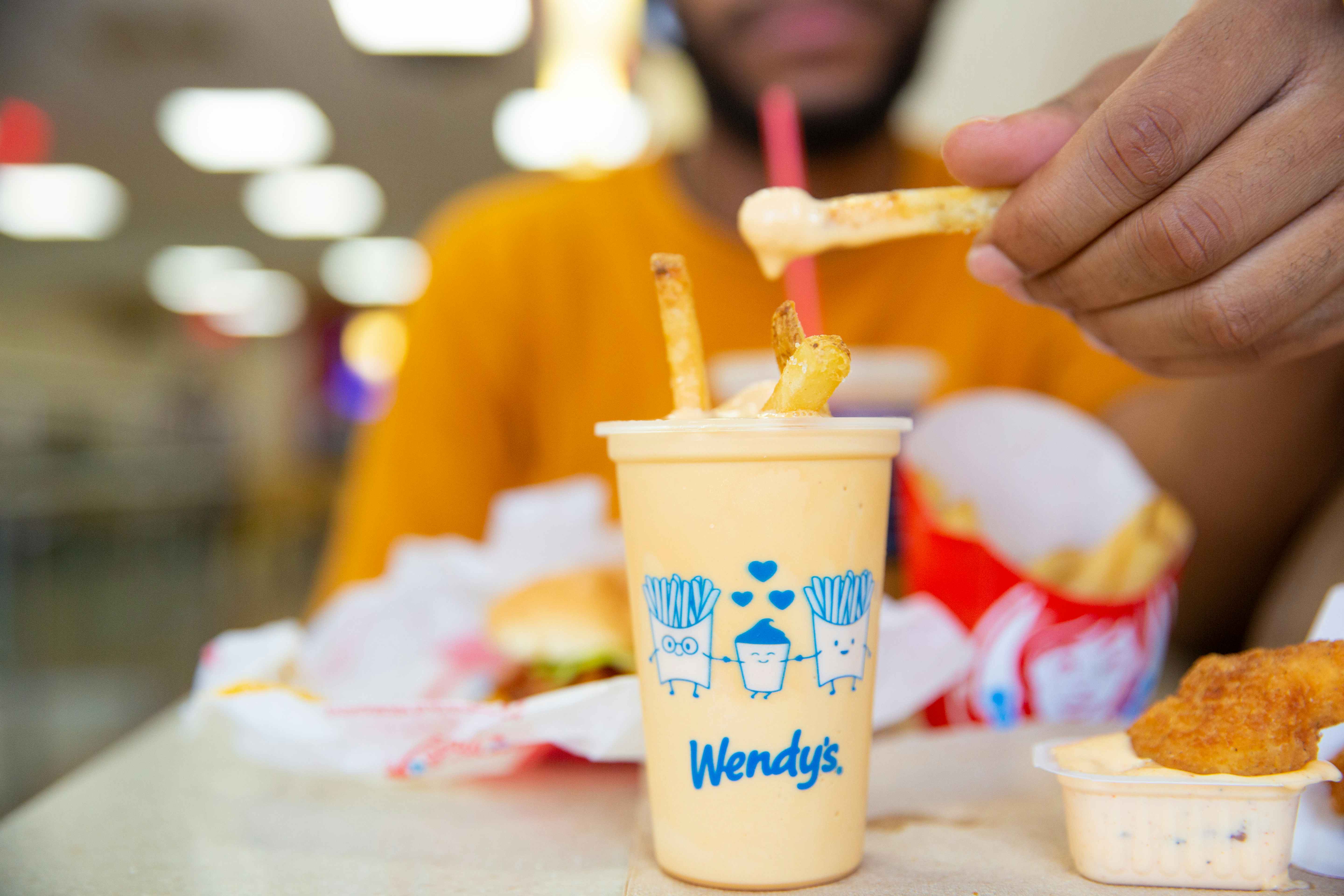 Person dipping fries into a wend'ys pumpkin spice frosty