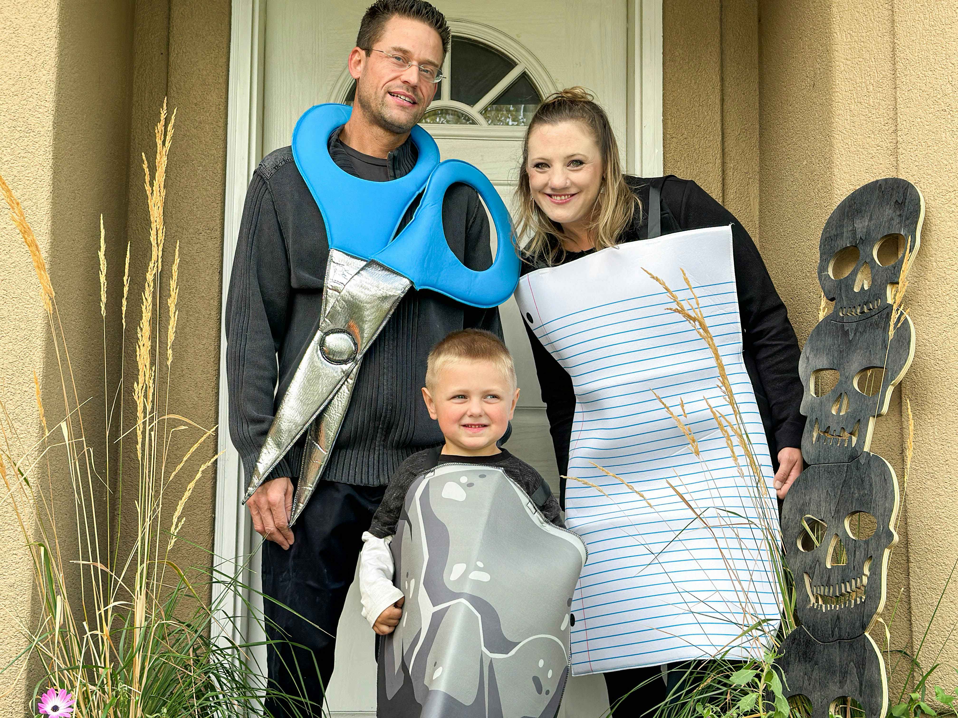 a family in a rock paper scissor costume in front of house door 
