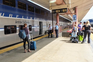 someone standing at an Amtrak station, holding their baggage