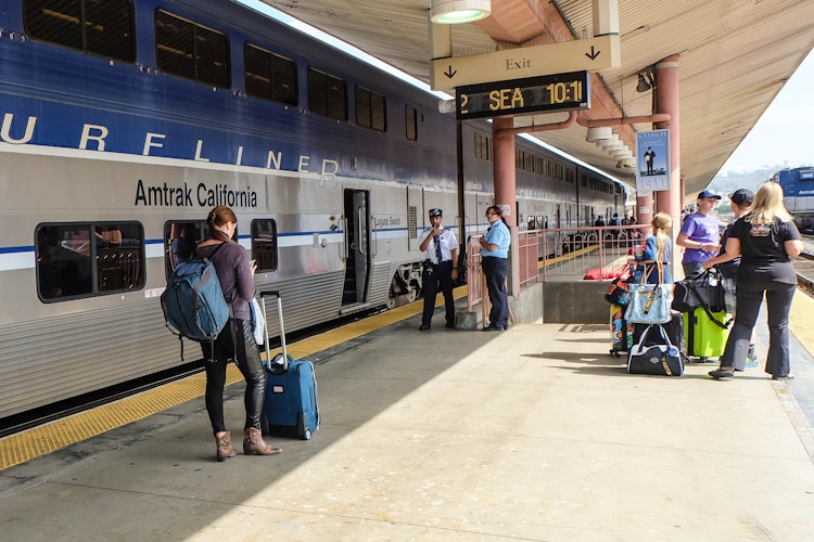 someone standing at an Amtrak station, holding their baggage
