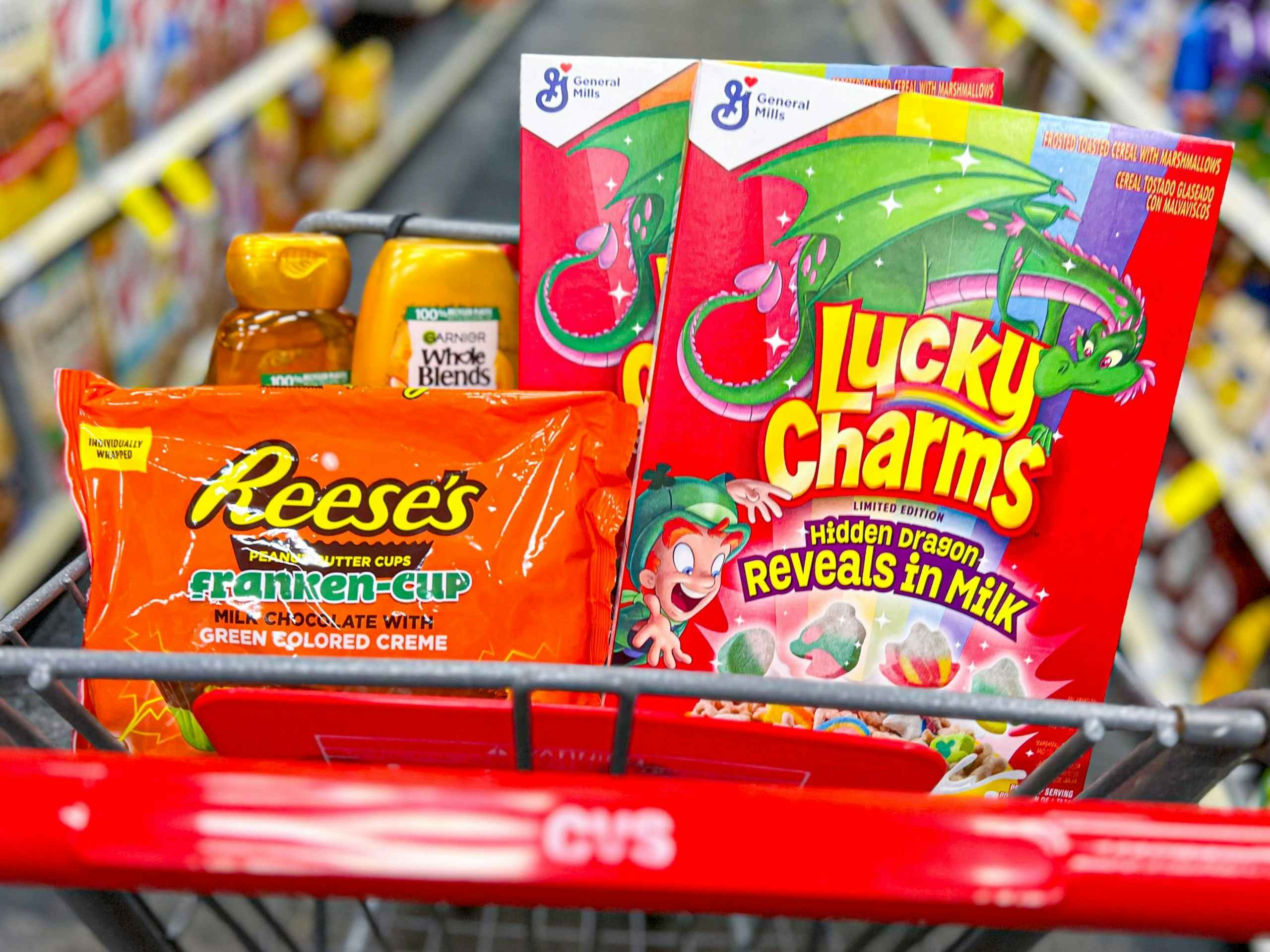 Reese's Franken-Cup candy bag, two Lucky Charms cereal boxes, and two Garnier Whole Blends bottles inside cart