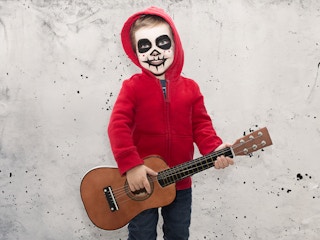 child dressed up for halloween like miguel from the movie coco