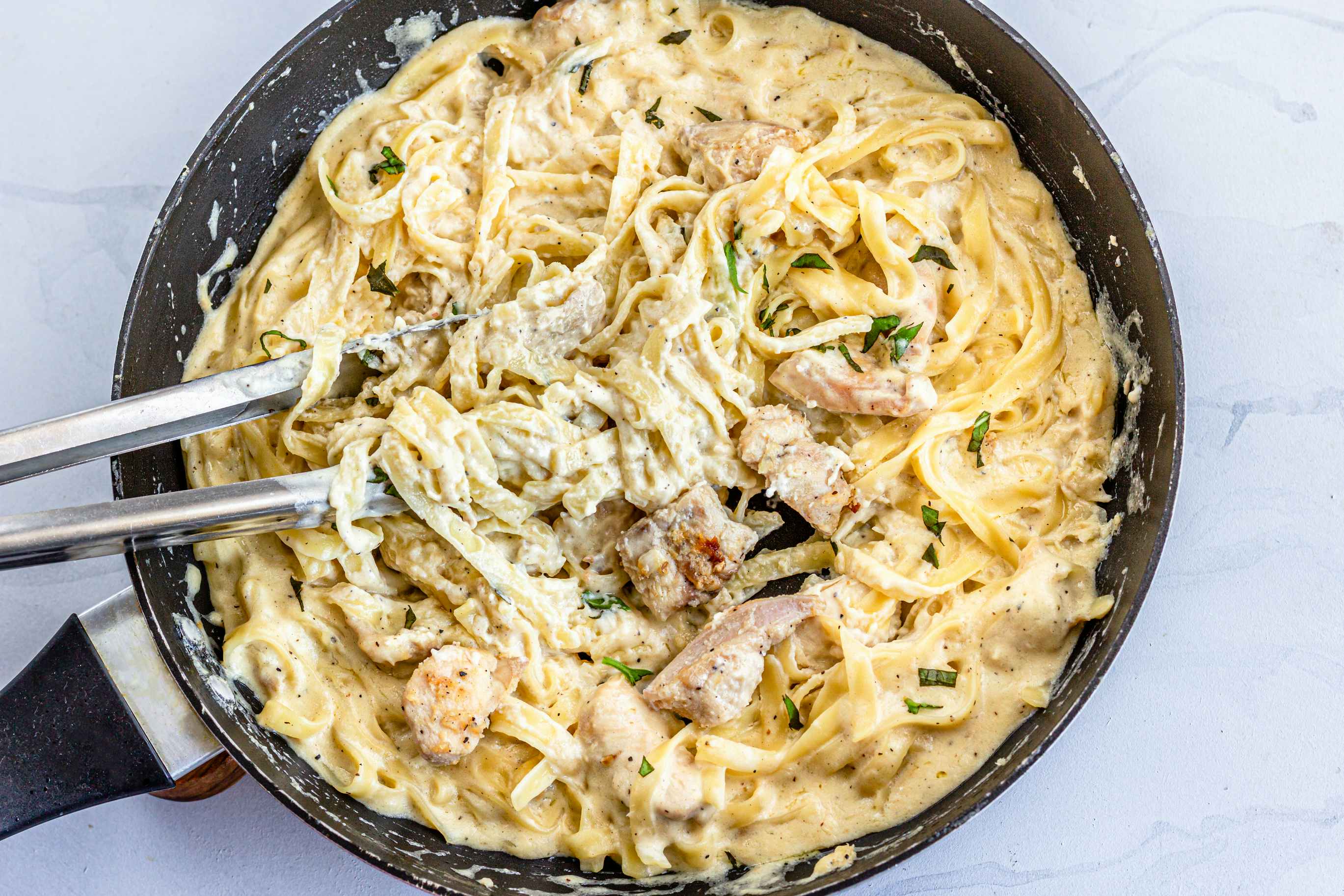 zchicken pasta in a skillet with togns