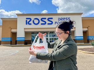 a person holding up a tj maxx bag in front of a ross sign