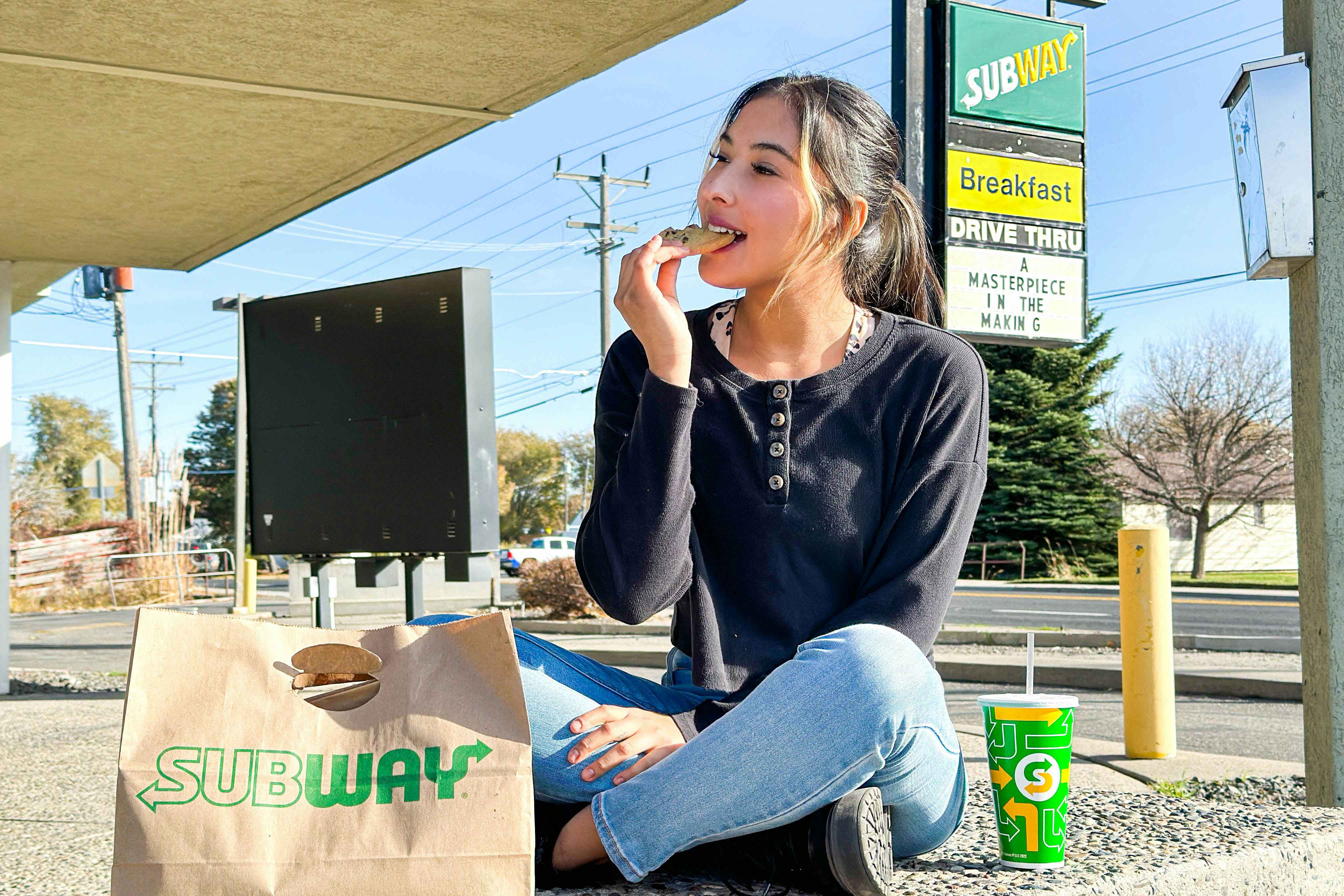 a woman eating a coffee outside subway