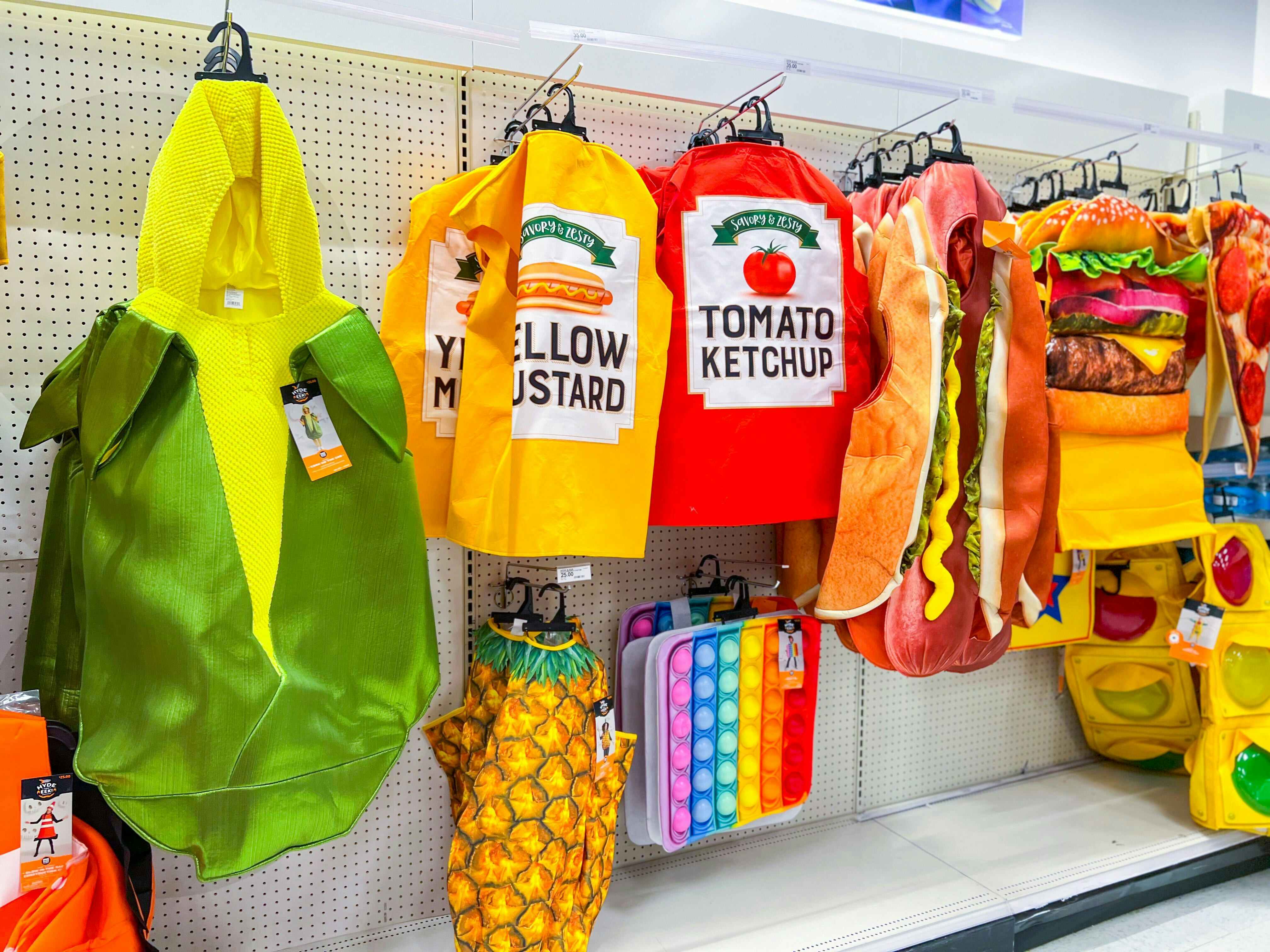 Target kids' halloween costumes on display: a corn on the cob, yellow mustard, ketchup, hot dog, and hamburger costume hanging up