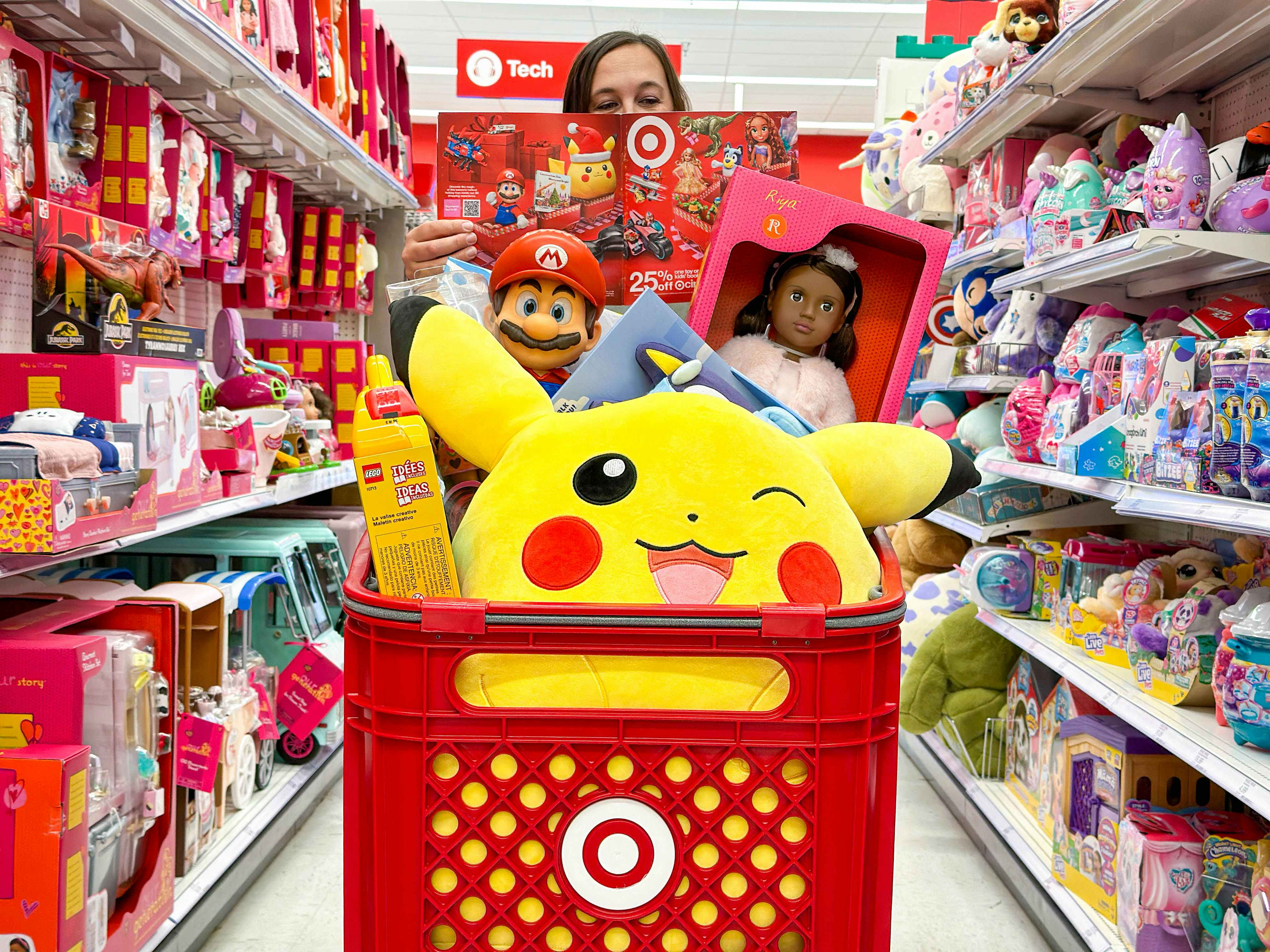 a woman holding a target toy book standing behind a target cart