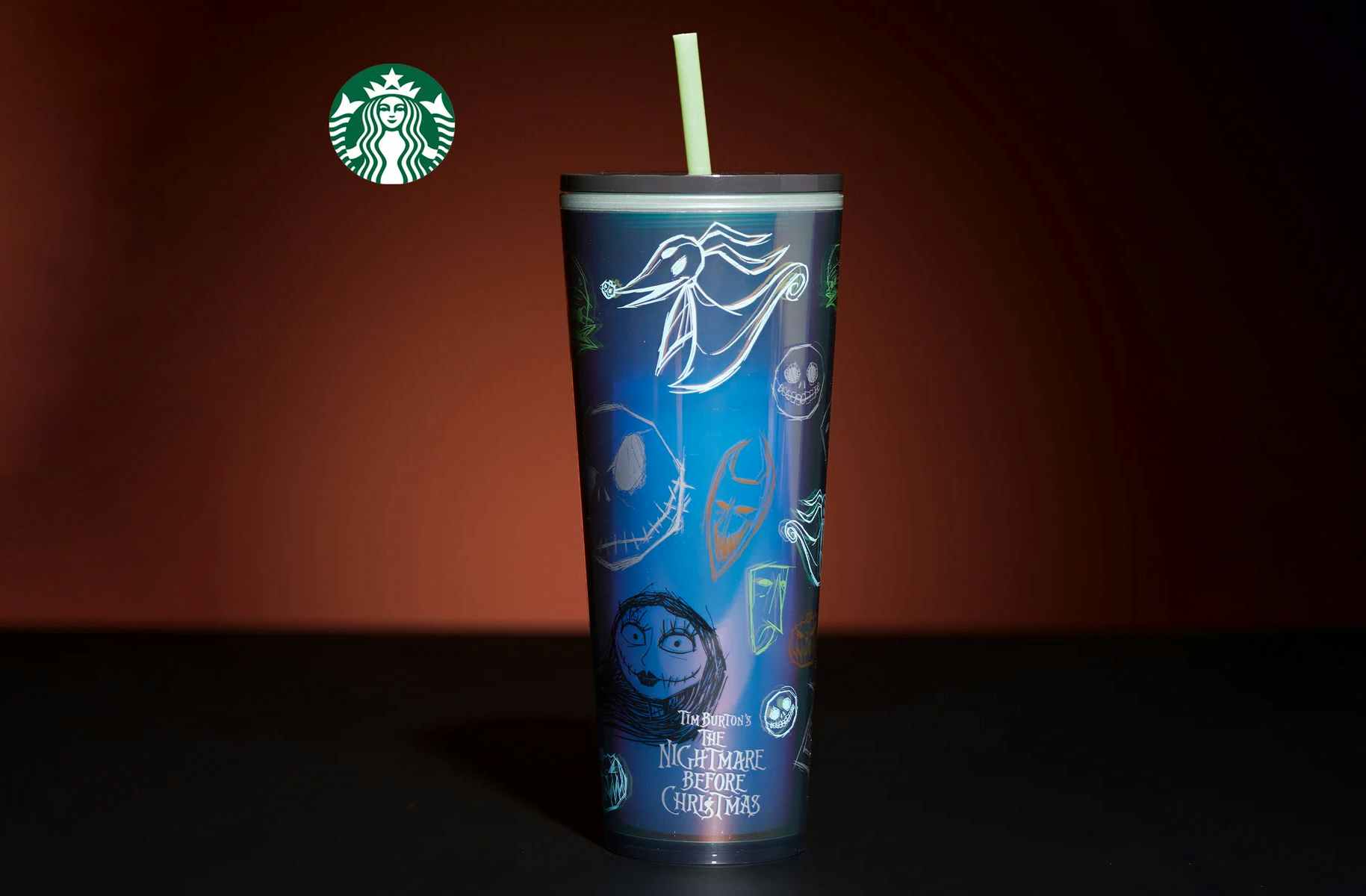 Blue cup with tim burtons nightmare before christmas characters on it against a grown background and next to the starbucks logo