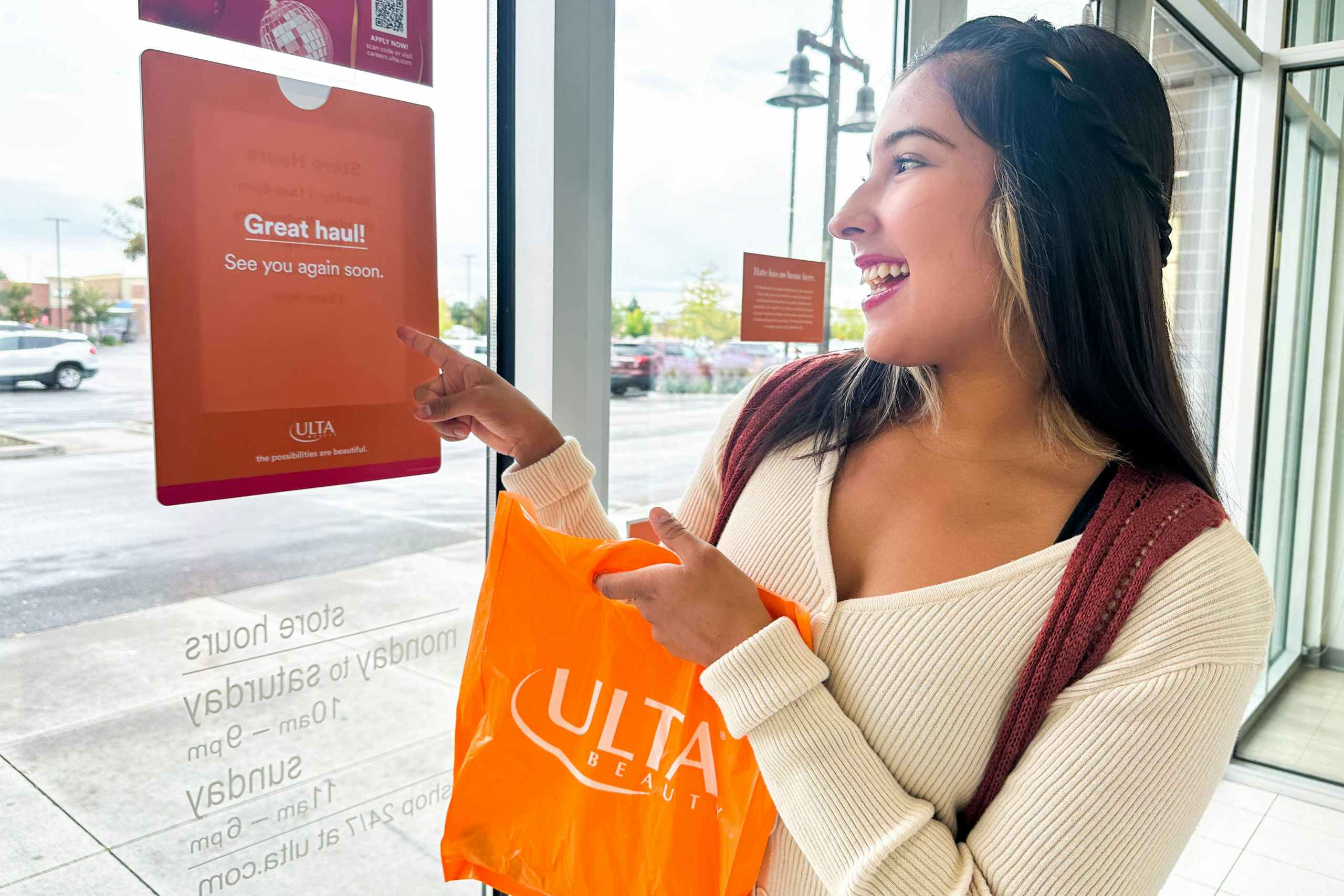 a woman looking at the ulta sign as she is leaving the store 