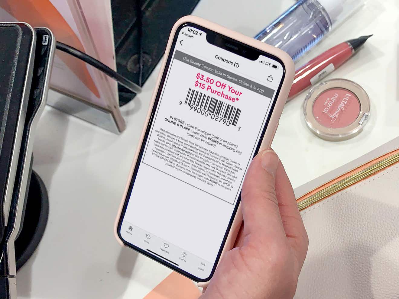 person with an ultamate rewards coupon on iphone checking out at ulta