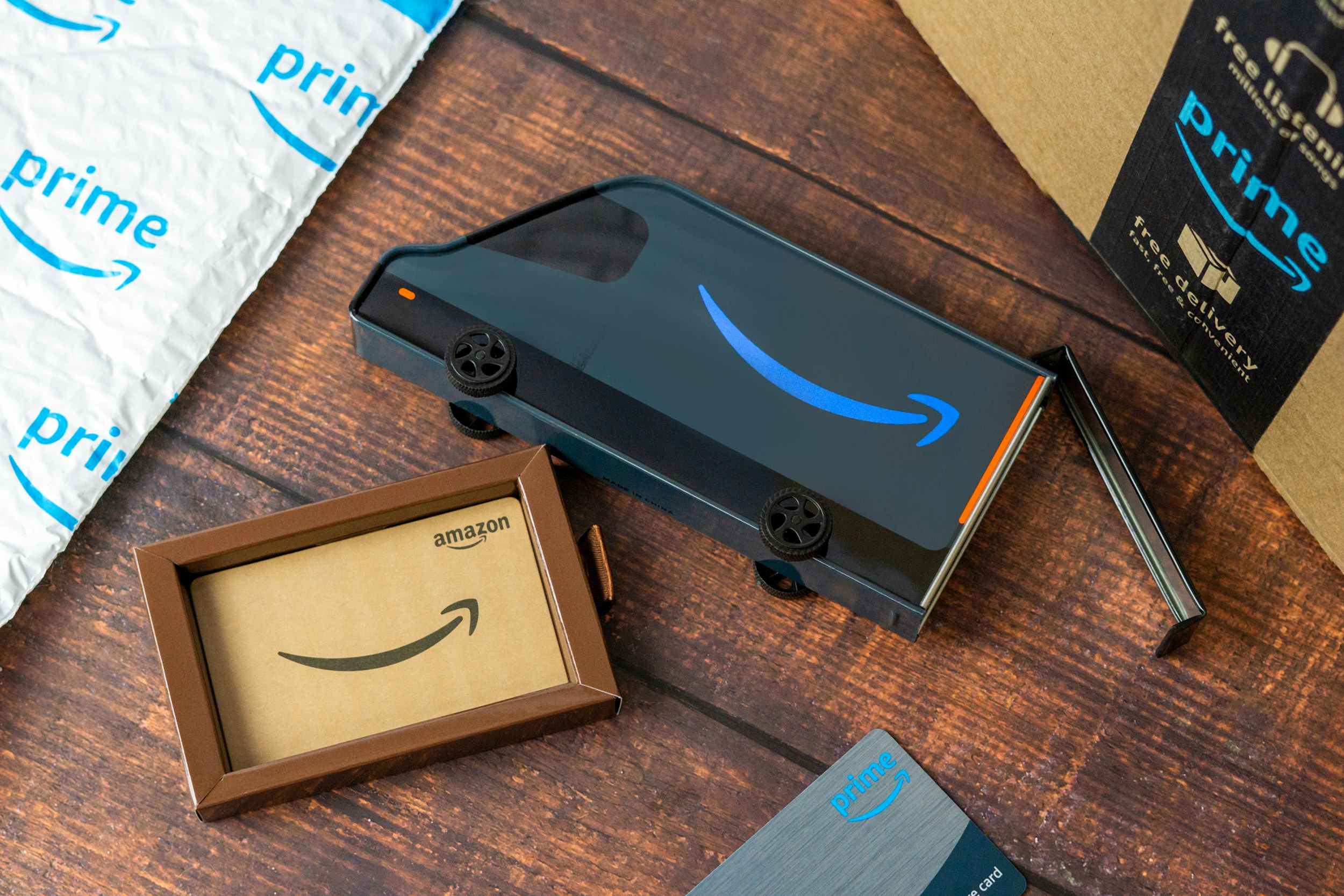 an Amazon limited edition gift card truck tin on a table next to some prime packages and store card