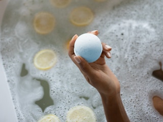 person in bath holding a bath bomb