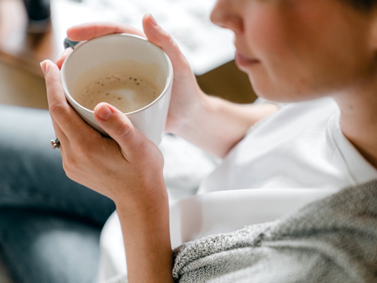 person holding a white mug with coffee