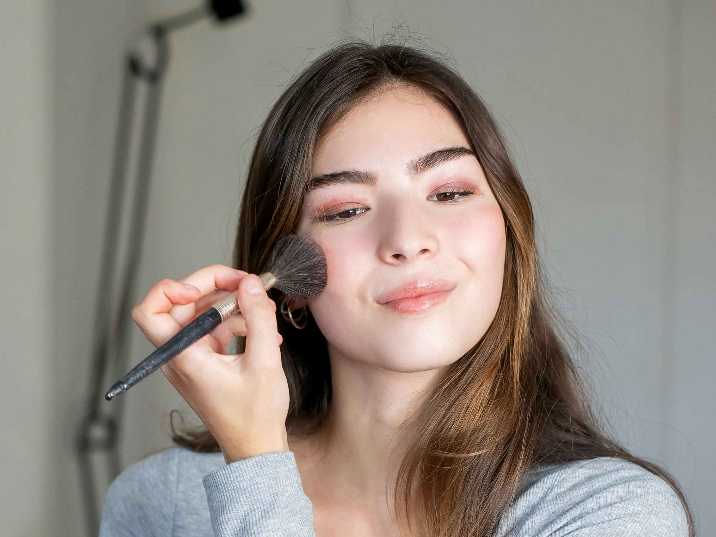 person using makeup brush to apply face powder