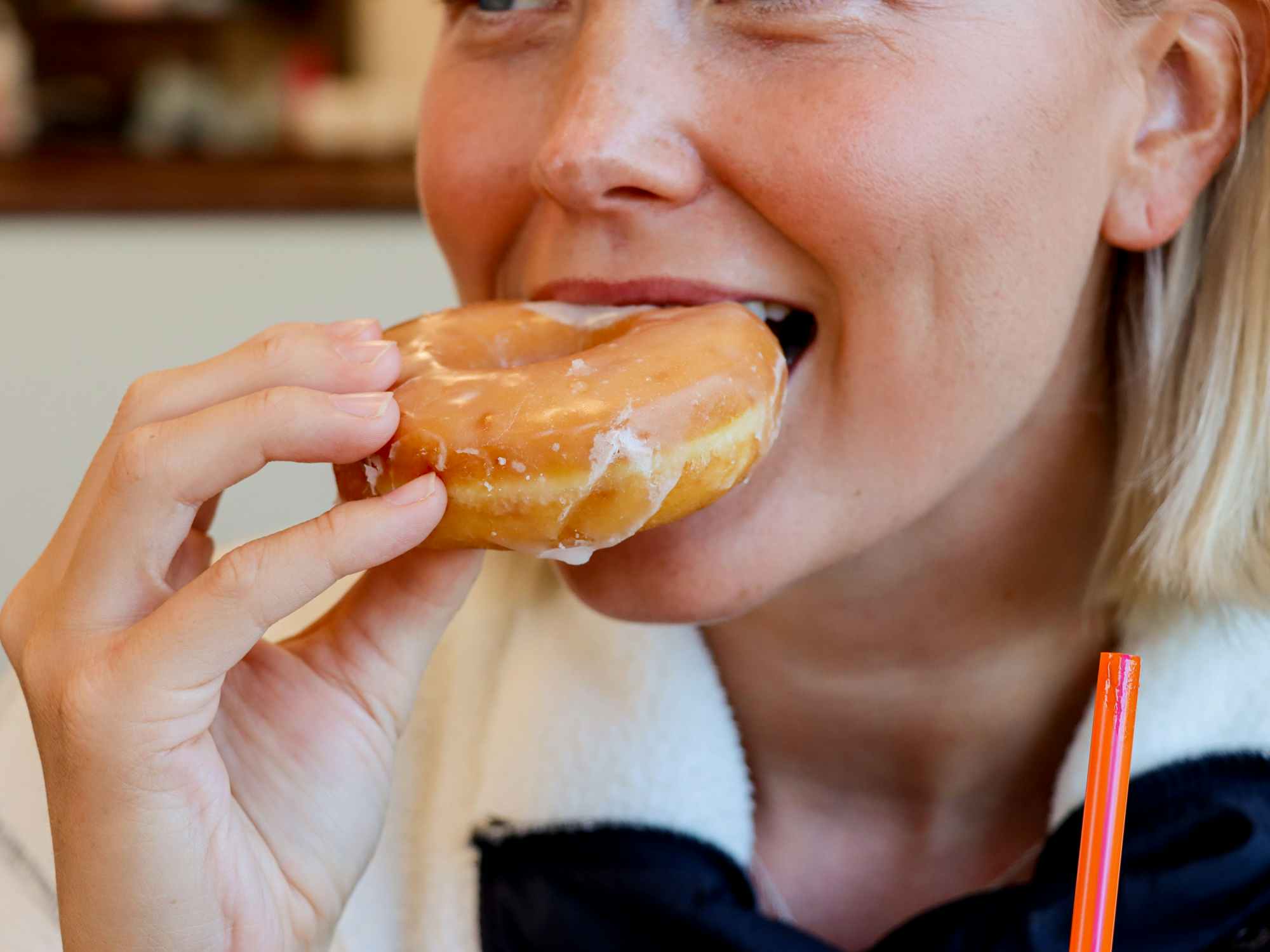 a person taking a bite out of a donut at dunkin donuts
