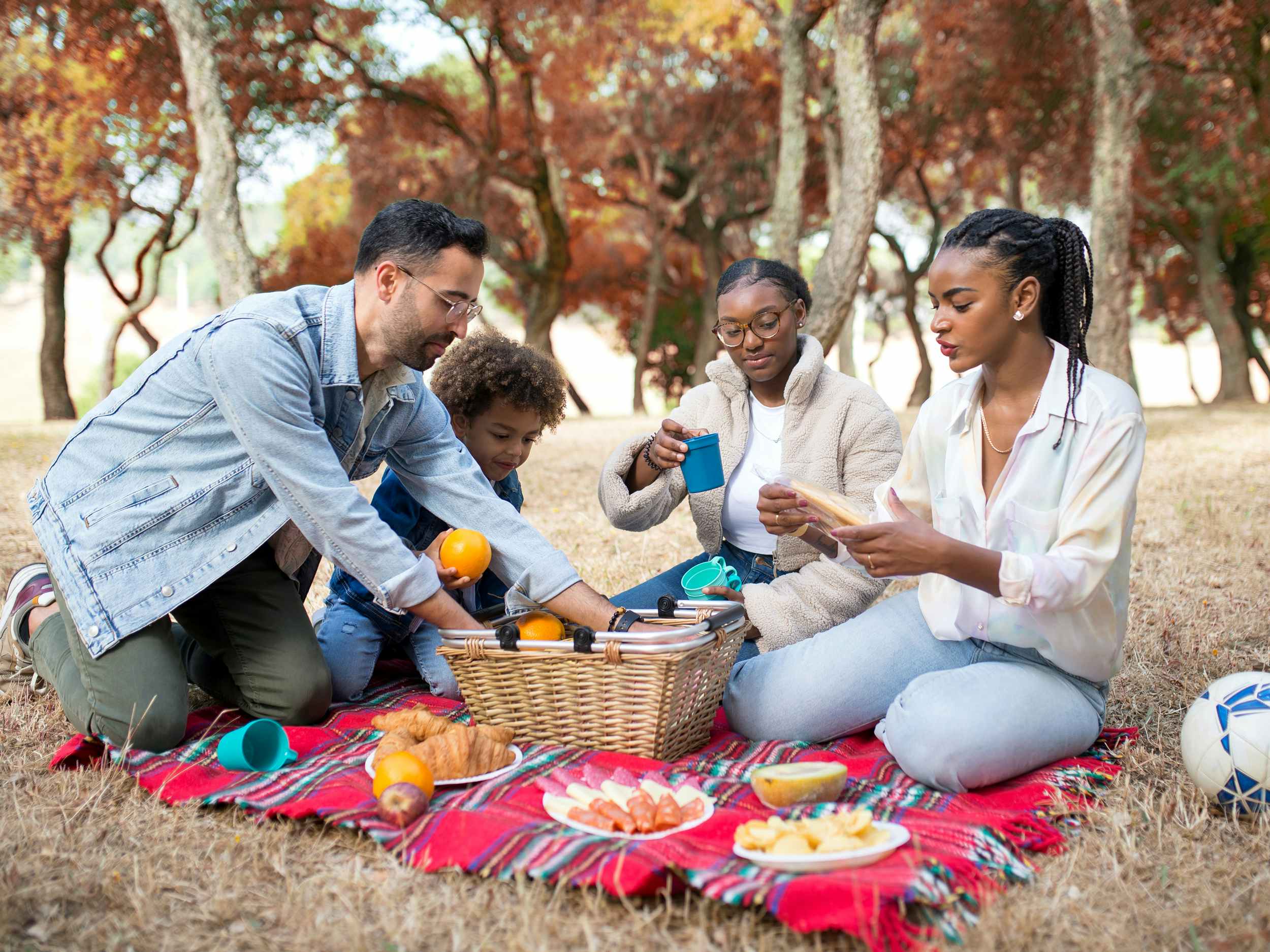 family of four having a fall picnic in the woods