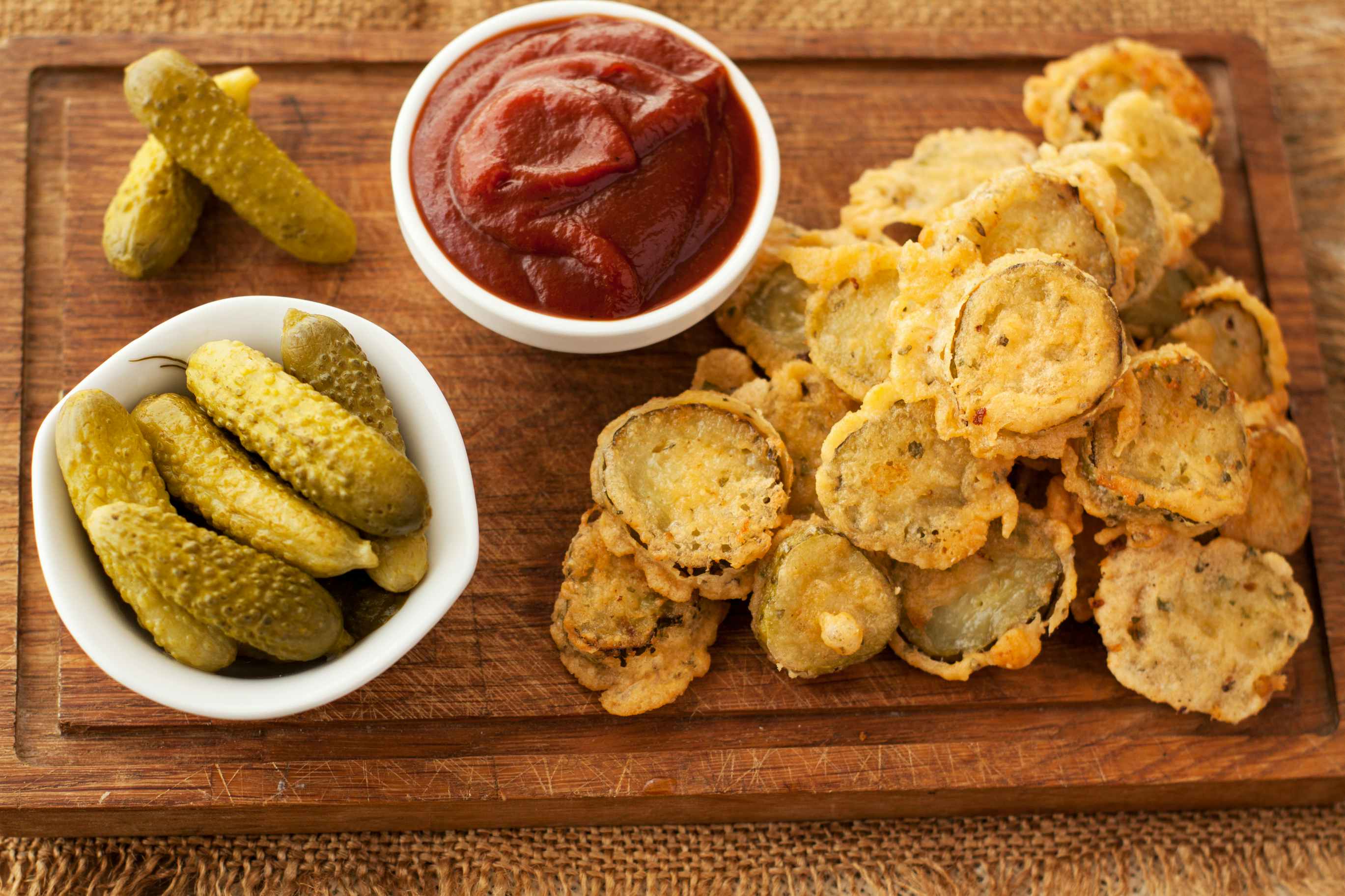 Fried pickles next to pickles and a bowl of ketchup