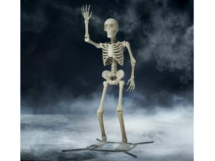 A plastic skeleton standing with his arm waving.