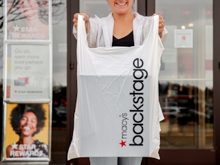a person holding a macy backstage bag outside store