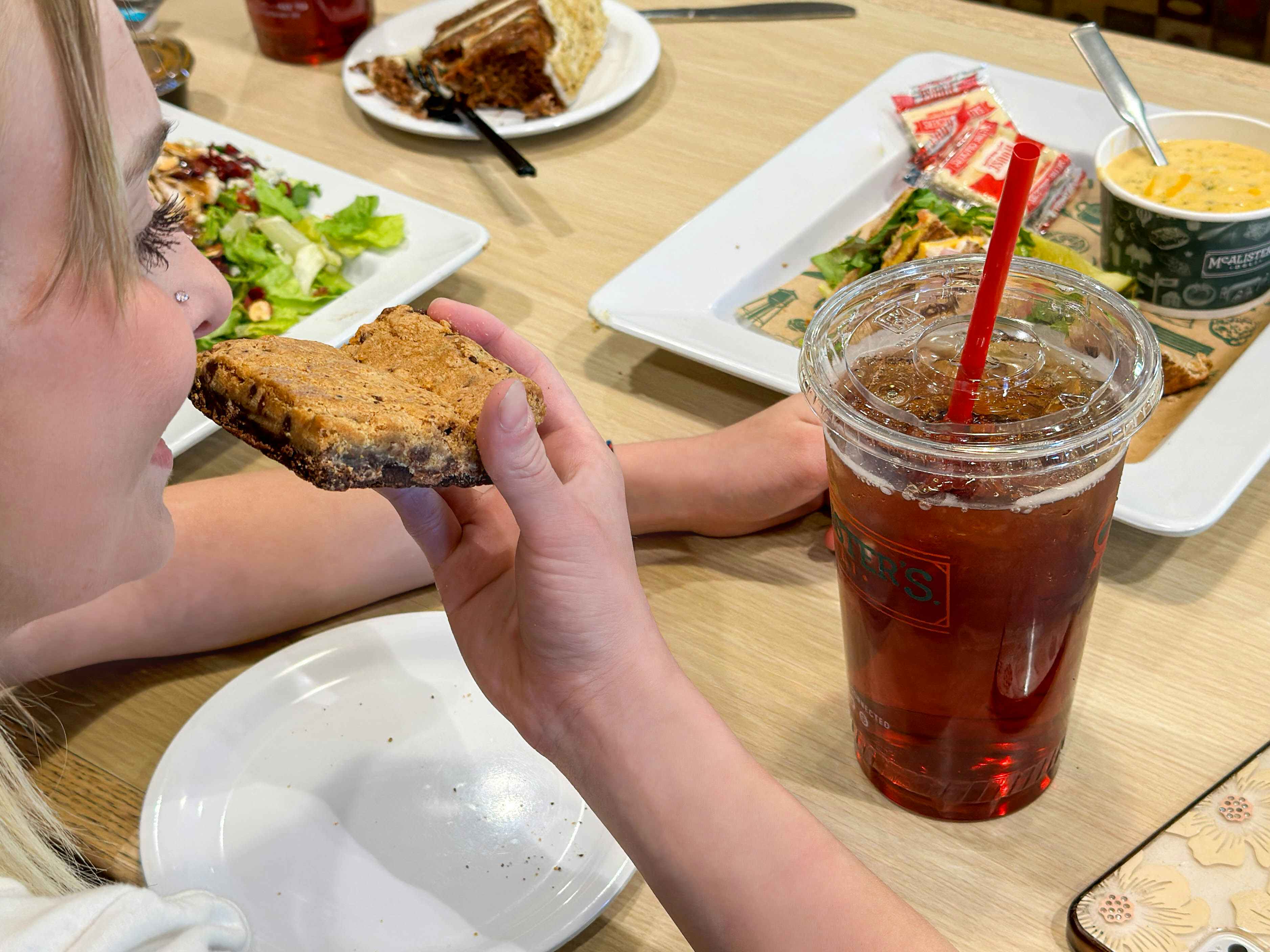 a person taking a bite of a brookie in mcalisters sitting at a table of food 