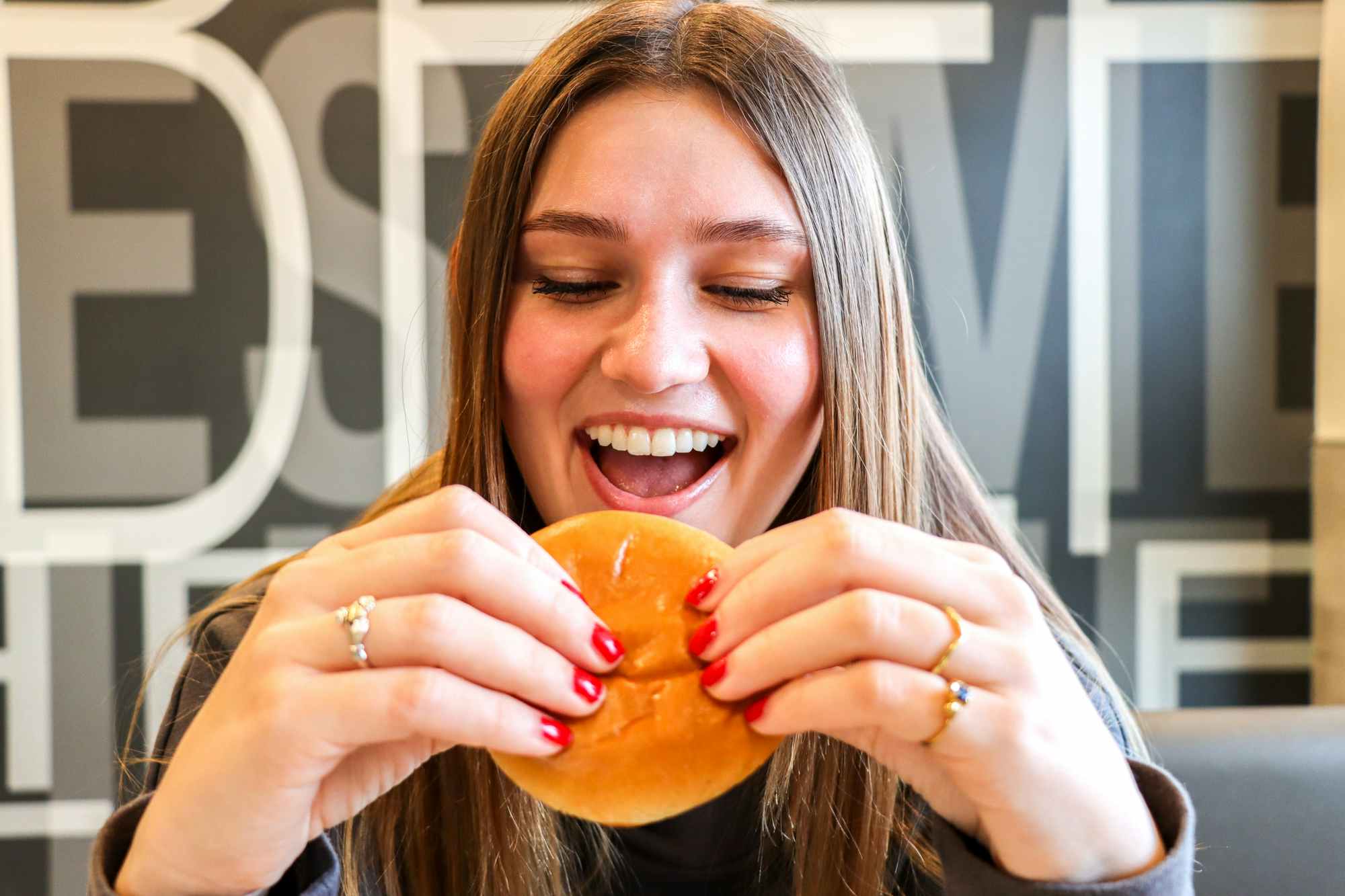 a person taking a bite of a mcdonalds hamburger