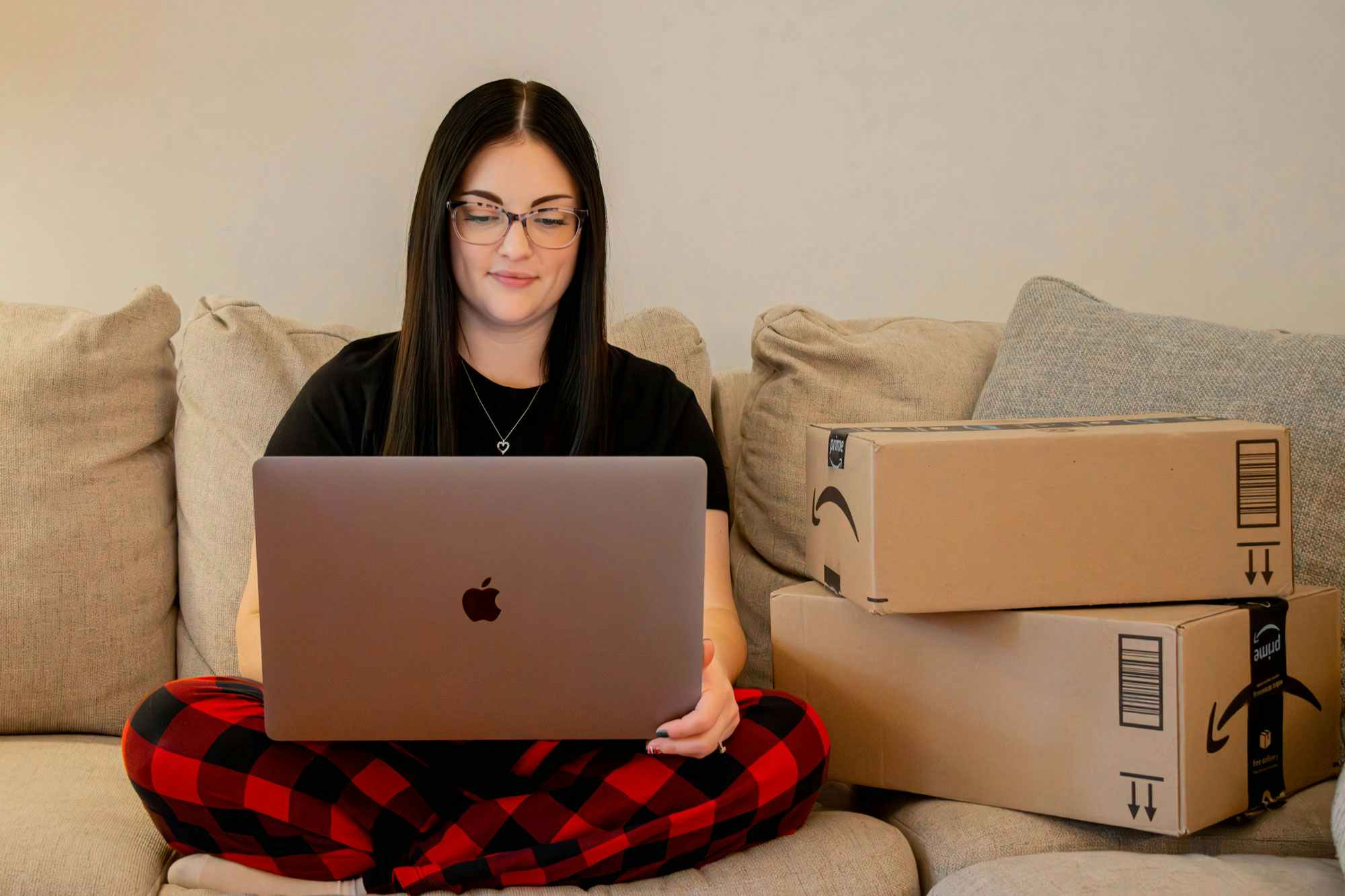a person looking at their laptop while sitting next to amazon boxes