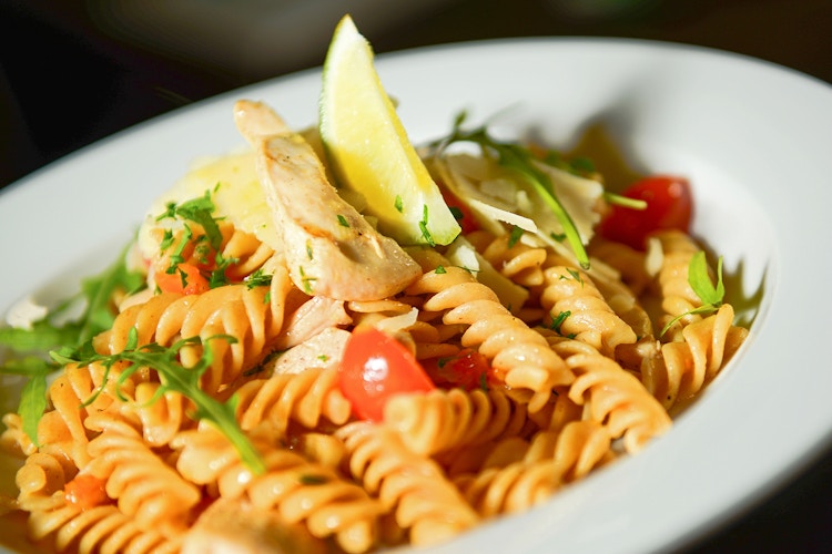 fusilli pasta dish with chicken, cherry tomatoes, greens, and lemon