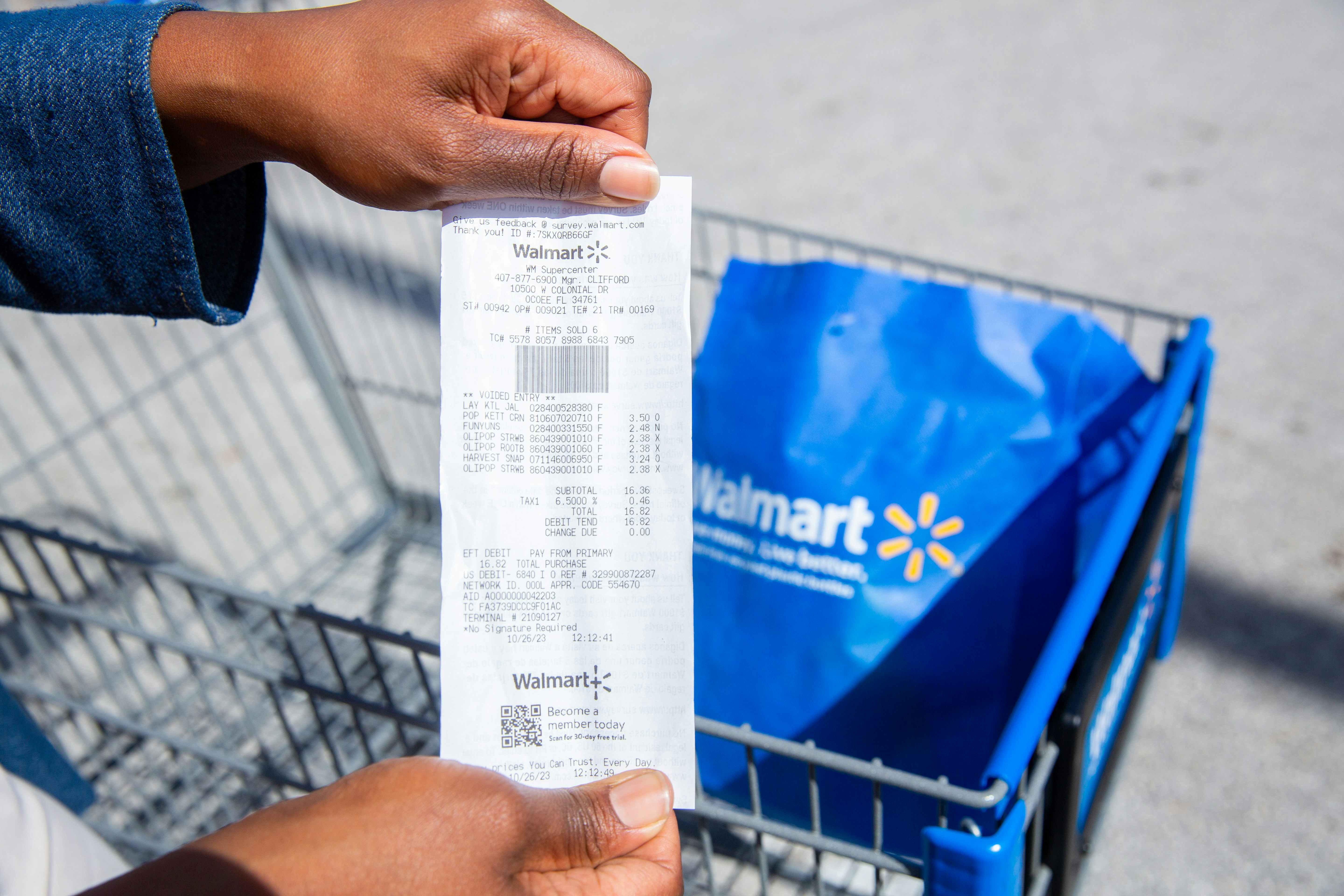 someone looking at their Walmart receipt with a reusable bag in a cart