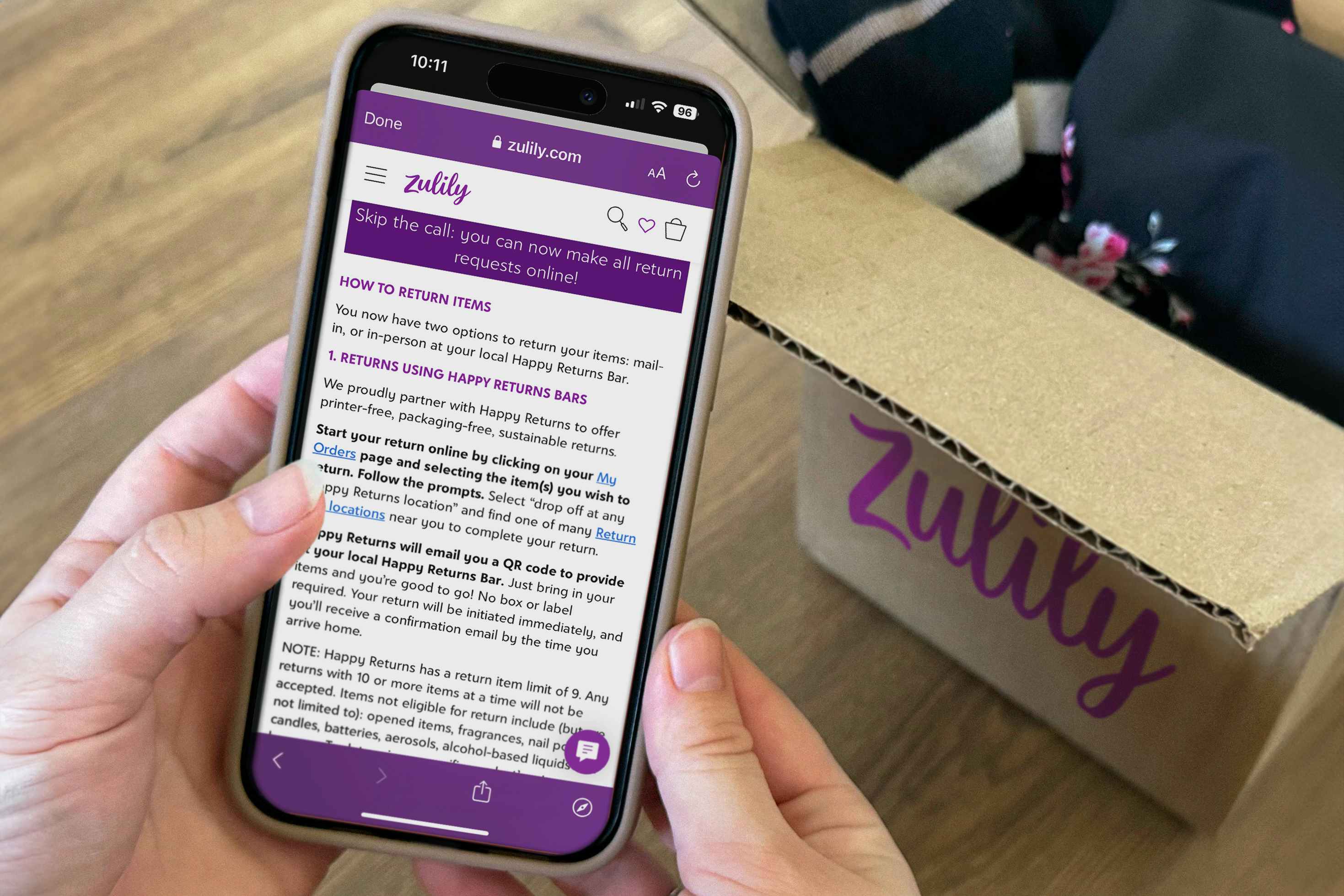 someone holding a phone displaying the Zulily return policy next to a box
