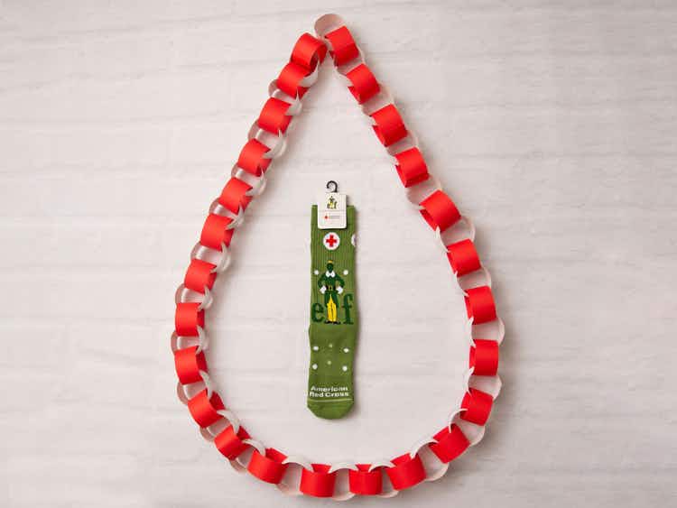 A pair of Buddy the elf socks in the middle of a paper chain shaped like a blood drop.