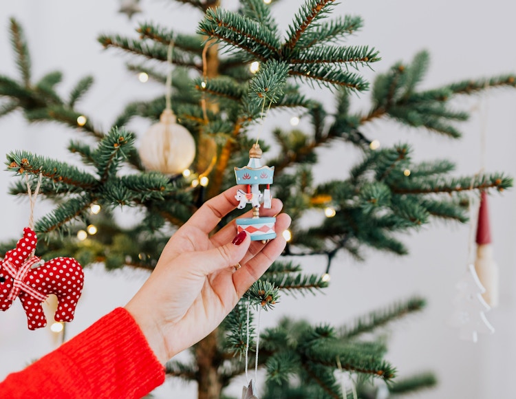 a christmas ornament being hung on a tree 