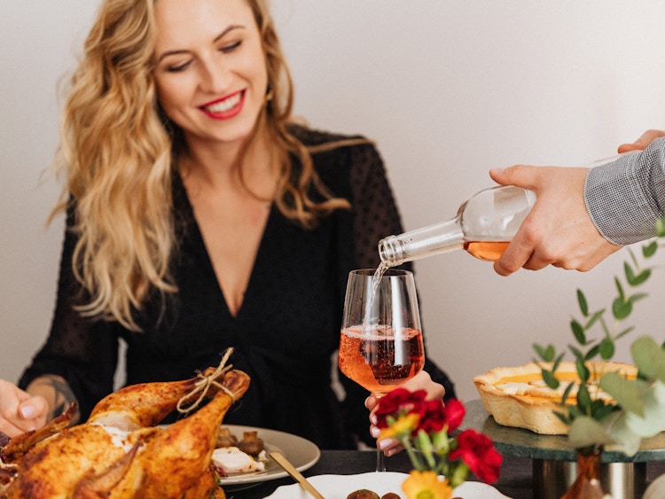 someone pouring sparkling wine into a glass at a holiday table