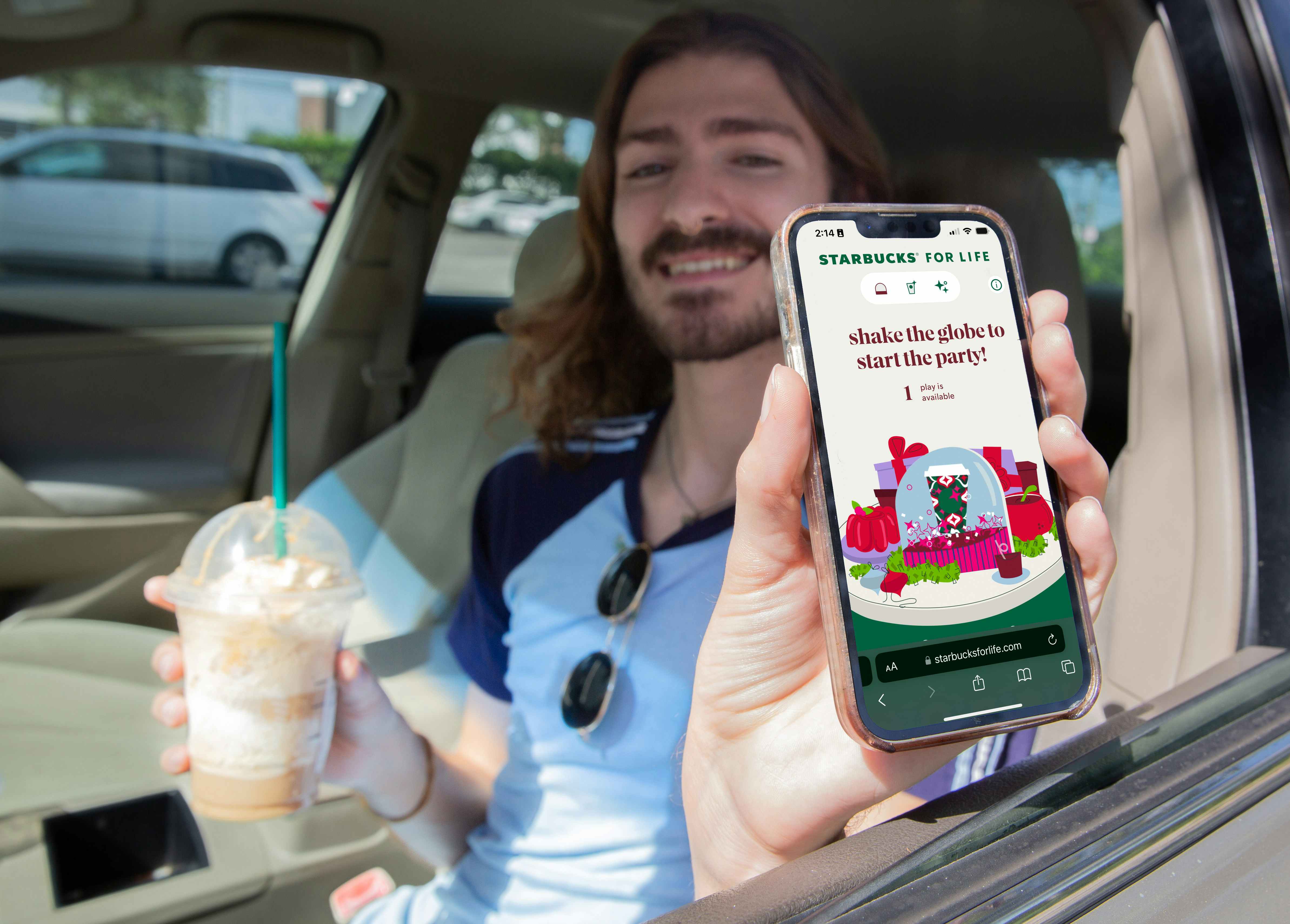 Person holding a phone while holding a starbucks cup while sitting in the car